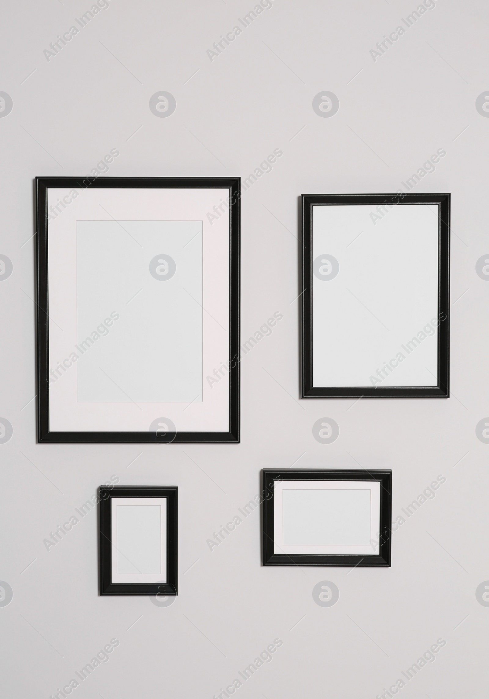 Photo of Different empty frames hanging on white wall