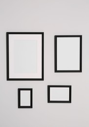 Different empty frames hanging on white wall