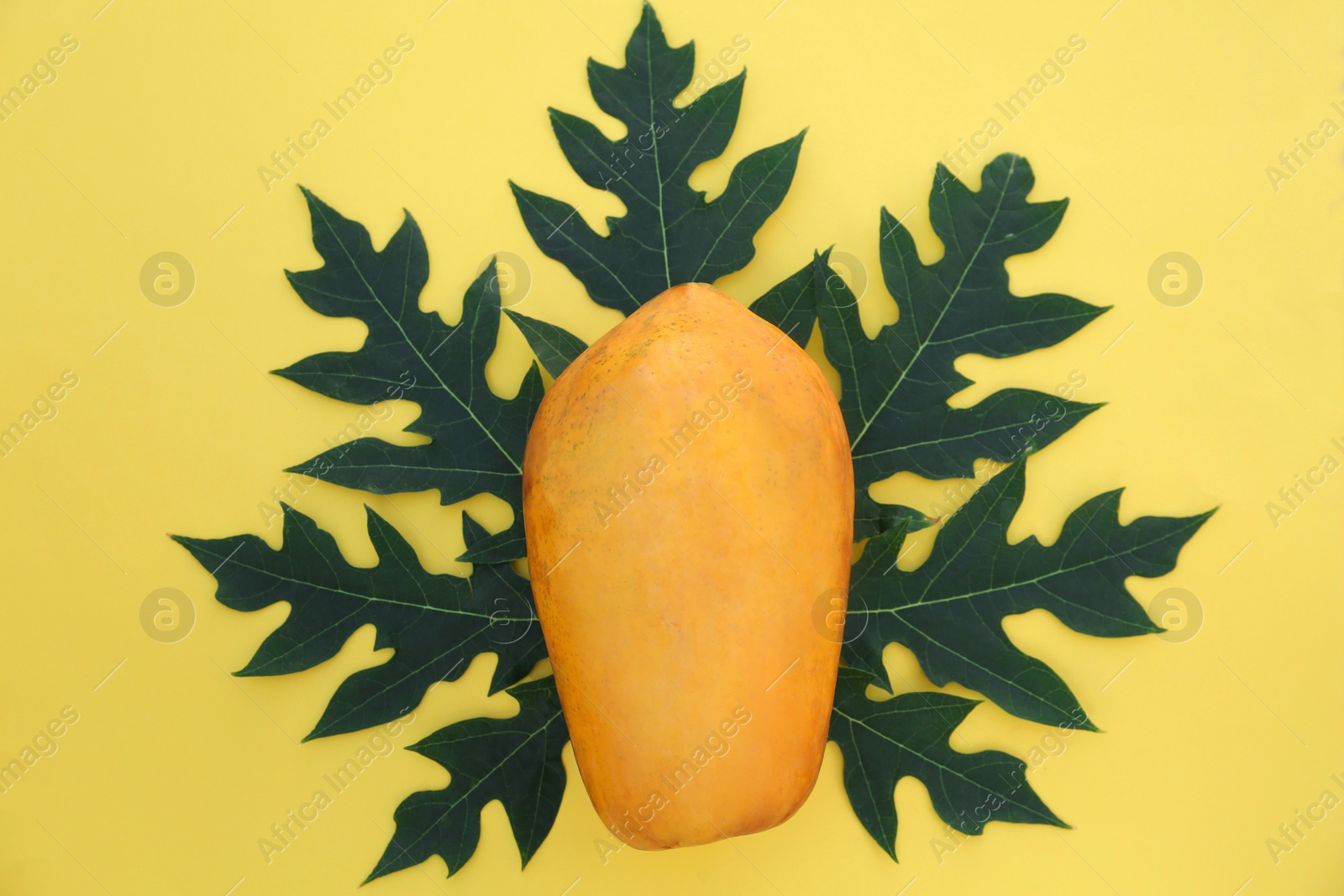 Photo of Fresh ripe whole papaya fruit and leaf on yellow background, top view