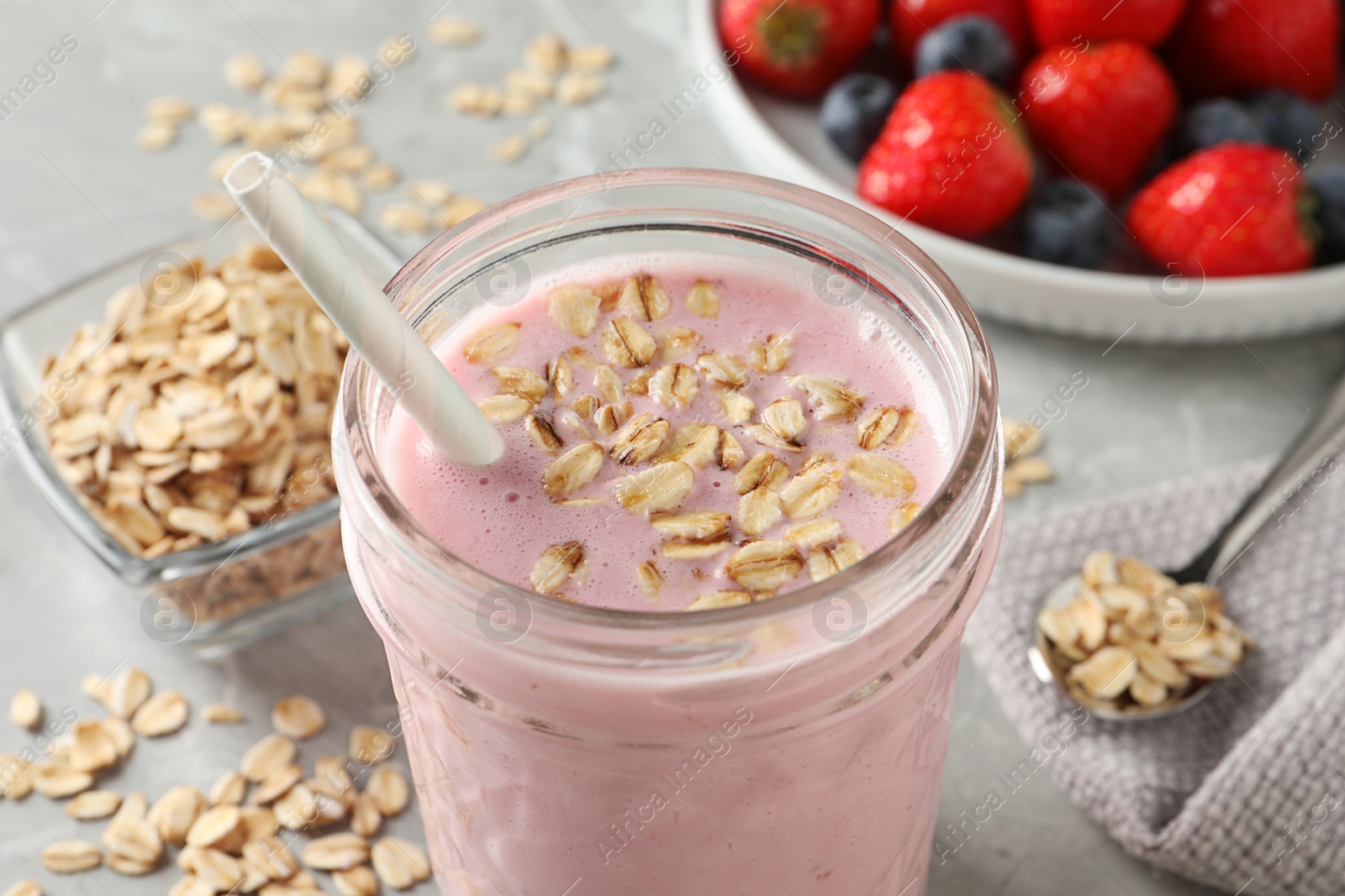 Photo of Jar of tasty berry oatmeal smoothie on grey table, closeup