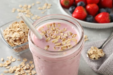 Photo of Jar of tasty berry oatmeal smoothie on grey table, closeup
