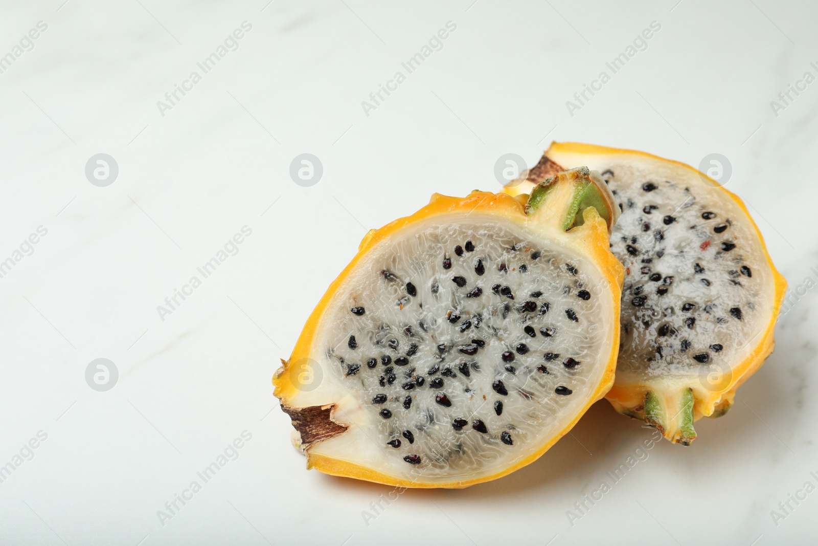 Photo of Delicious cut dragon fruit (pitahaya) on white marble table. Space for text