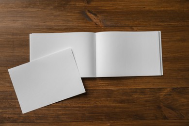 Sheet of paper and blank brochure on wooden table, flat lay. Mockup for design