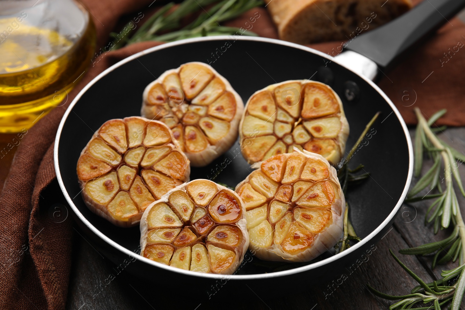 Photo of Frying pan with fried garlic on table, closeup