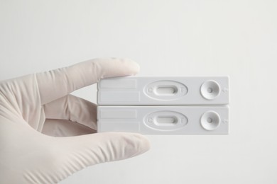 Photo of Doctor holding two disposable express tests for hepatitis on white background, closeup