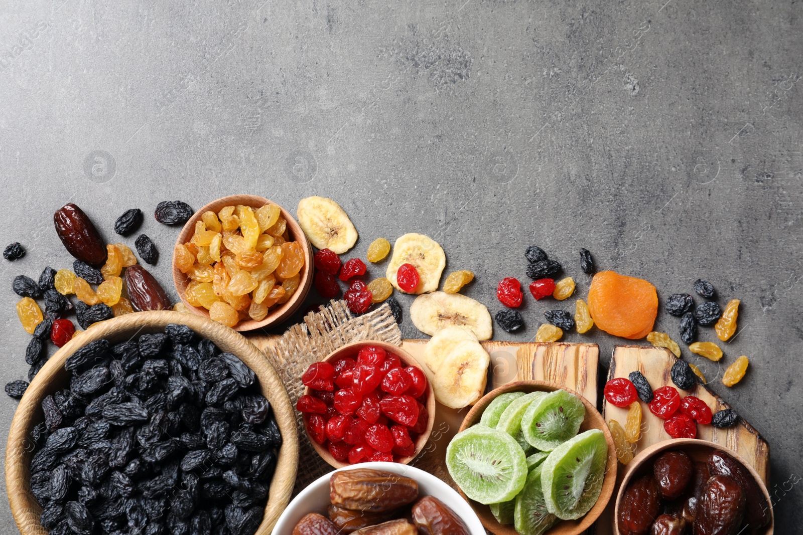 Photo of Bowls of different dried fruits on grey background, top view with space for text. Healthy food