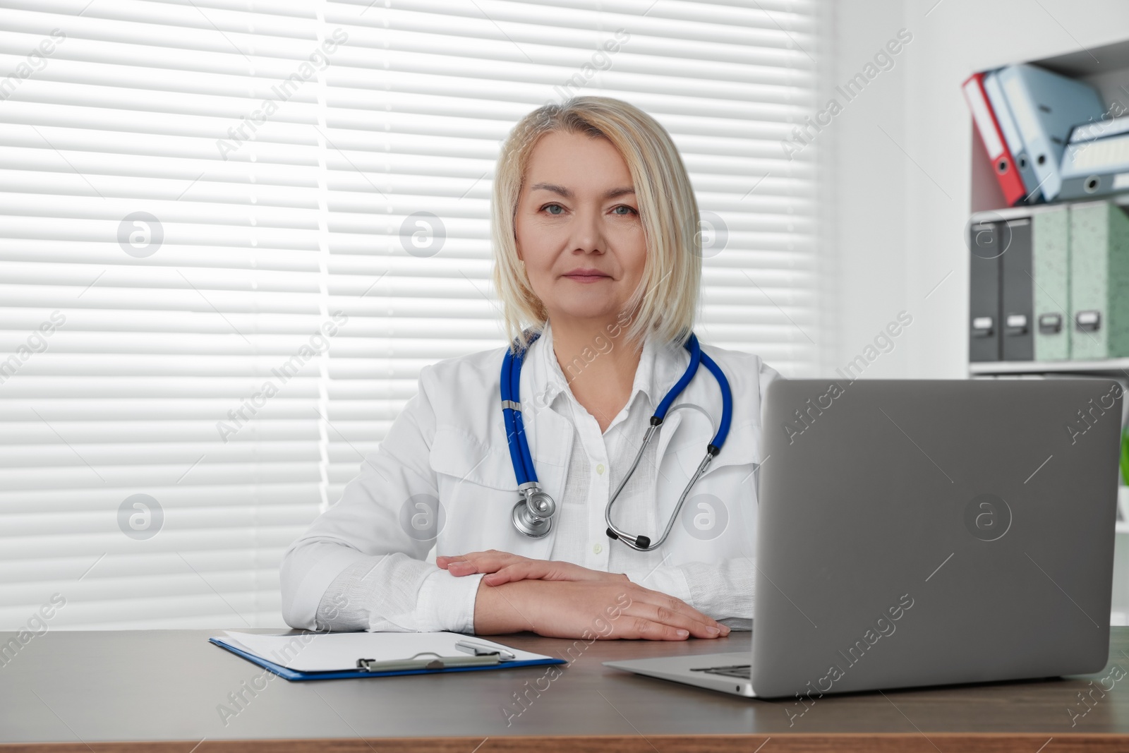 Photo of Doctor sitting at wooden table in clinic