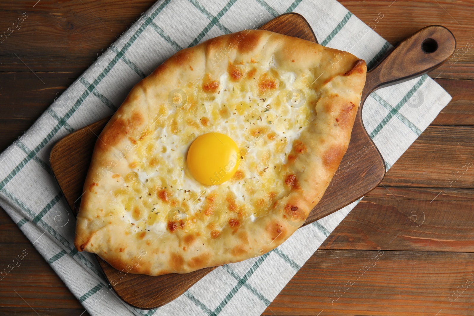 Photo of Fresh homemade khachapuri with cheese and egg on wooden table, top view