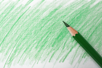 Green pencil on sheet of paper with drawing, top view