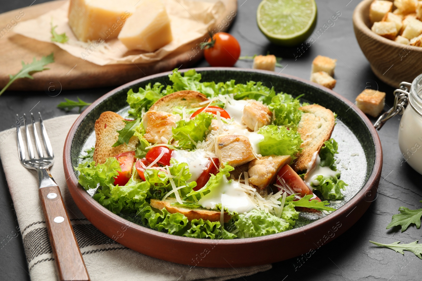 Photo of Delicious fresh Caesar salad on black table