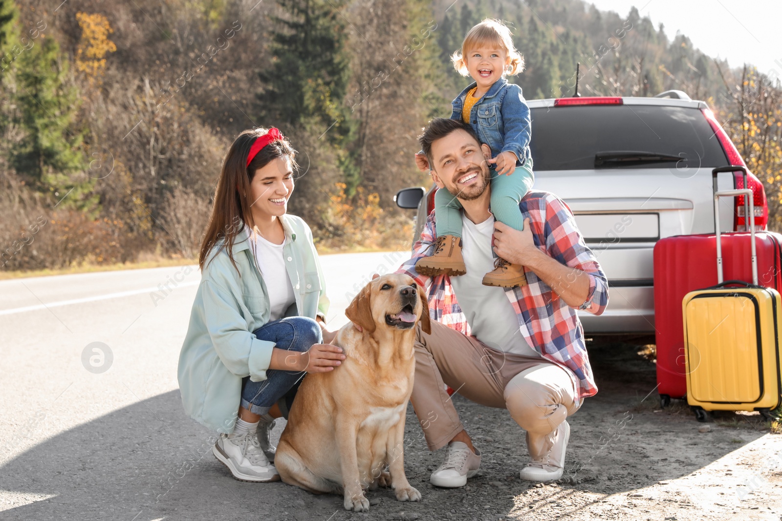 Photo of Parents, their daughter and dog near road. Family traveling with pet