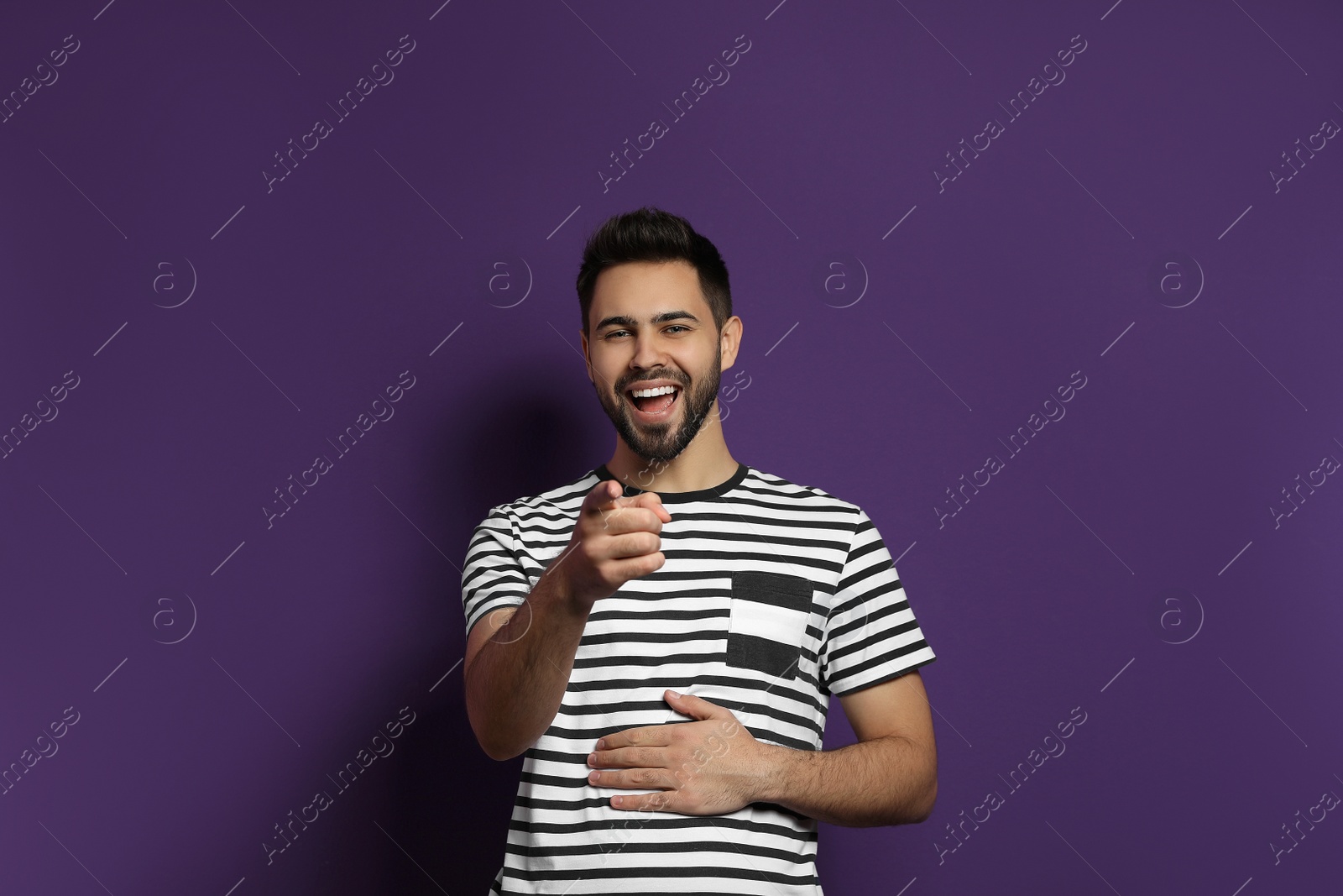 Photo of Young man laughing on purple background. Funny joke