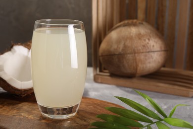 Photo of Glass of coconut water, palm leaf and nuts on grey table. Space for text