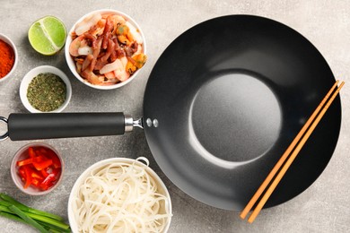 Flat lay composition with black wok, spices and products on grey textured table