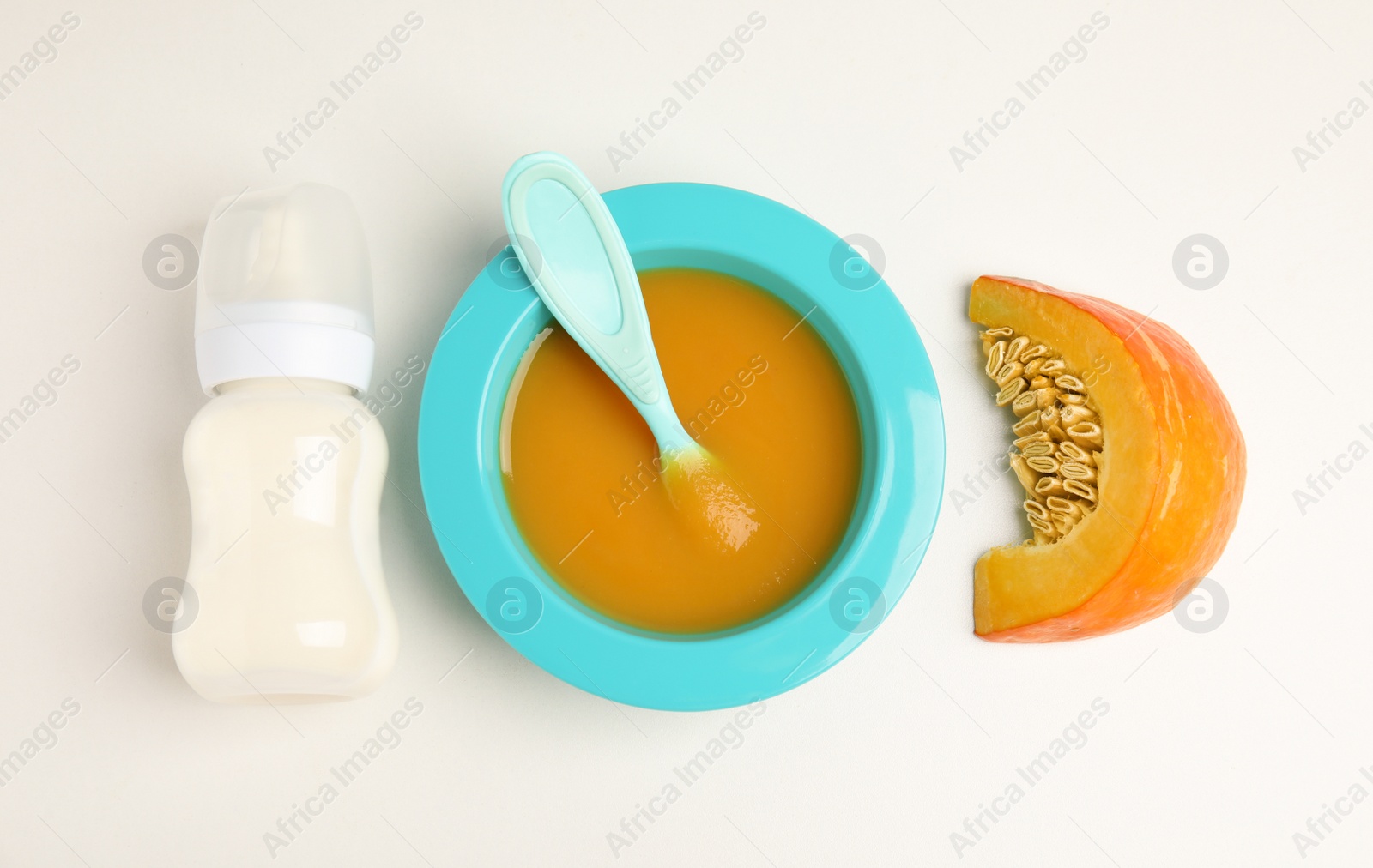 Photo of Baby food in bowl and fresh ingredients on white table, flat lay