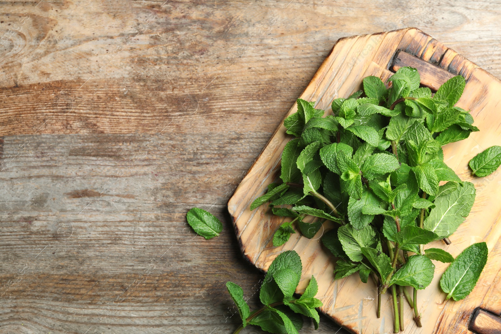 Photo of Board with fresh green mint on wooden table, top view. Space for text