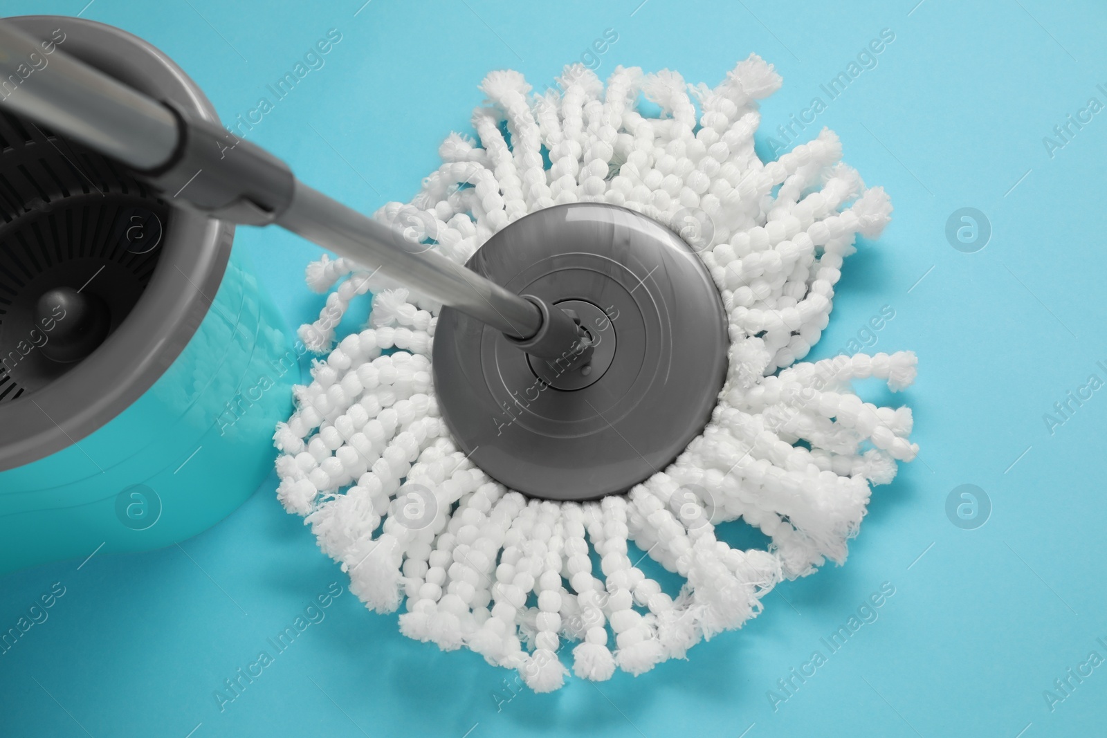 Photo of Mop and plastic bucket on light blue background, above view