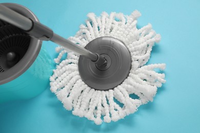 Mop and plastic bucket on light blue background, above view