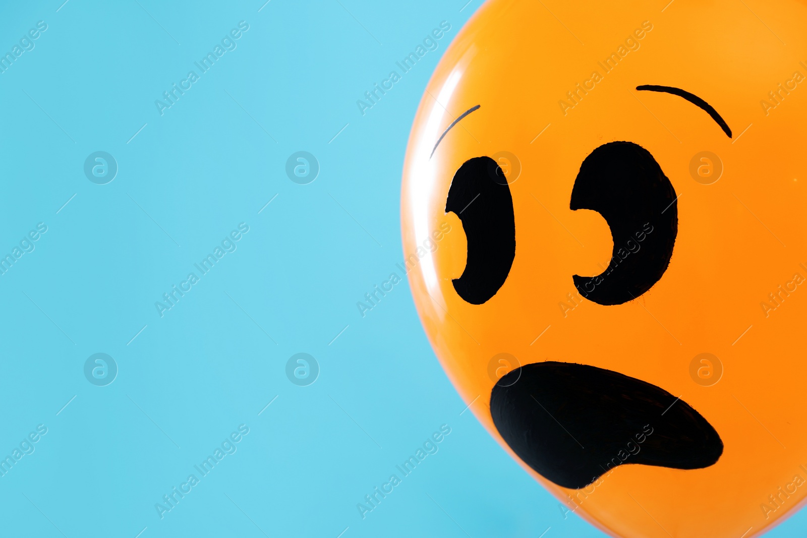 Photo of Orange balloon with drawing of scared face on blue background, space for text. Halloween party