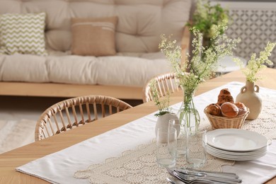 Photo of Clean dishes, flowers and fresh pastries on table in stylish dining room