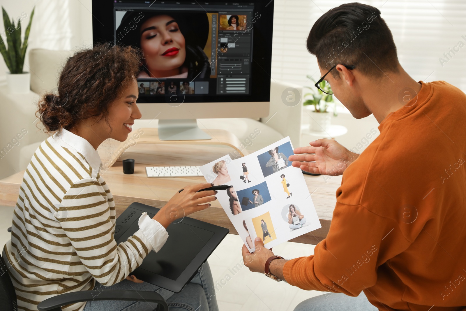 Photo of Professional retoucher with colleague working at desk in office