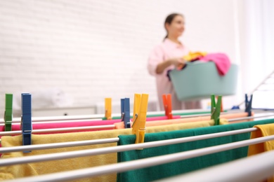 Woman with laundry basket indoors, focus on drying rack. space for text