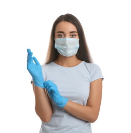 Woman in protective face mask putting on medical gloves against white background