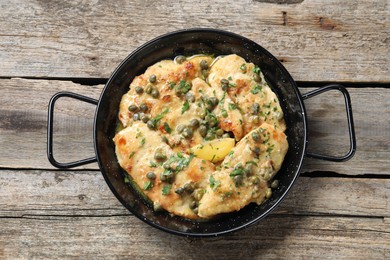 Photo of Delicious chicken piccata with herbs on wooden table, top view