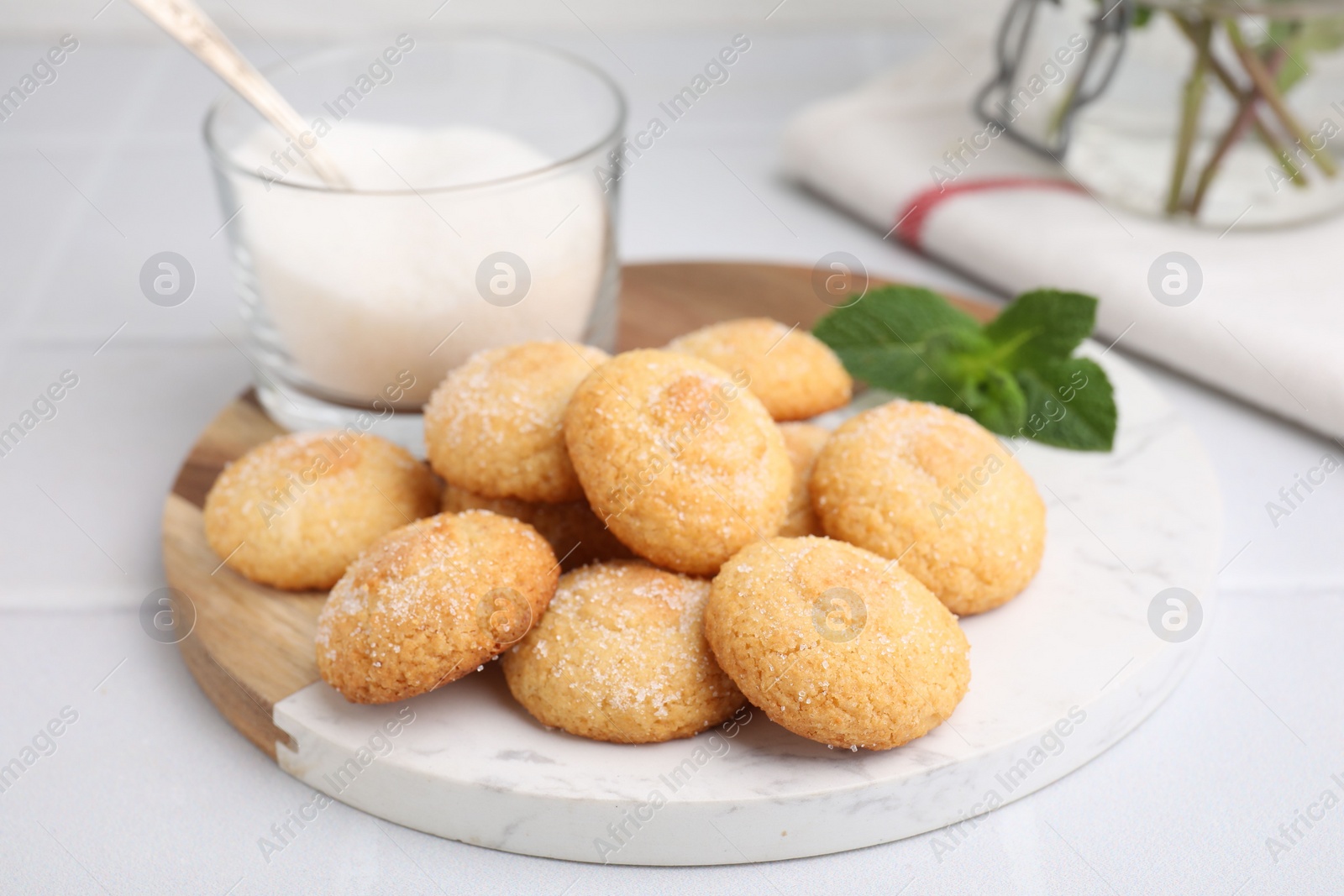 Photo of Tasty sweet sugar cookies, milk and mint on white tiled table, closeup