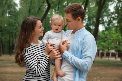 Photo of Parents with their cute baby spending time together outdoors. Happy family