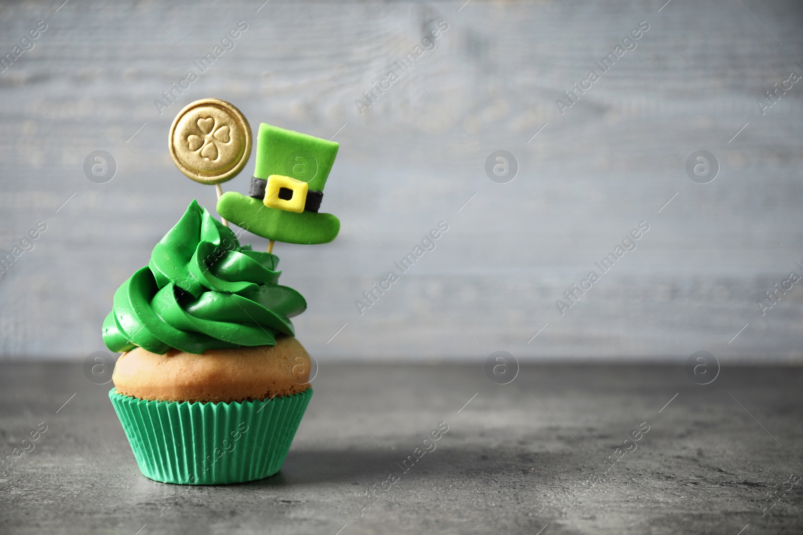 Photo of Decorated cupcake on grey table, space for text. St. Patrick's Day celebration