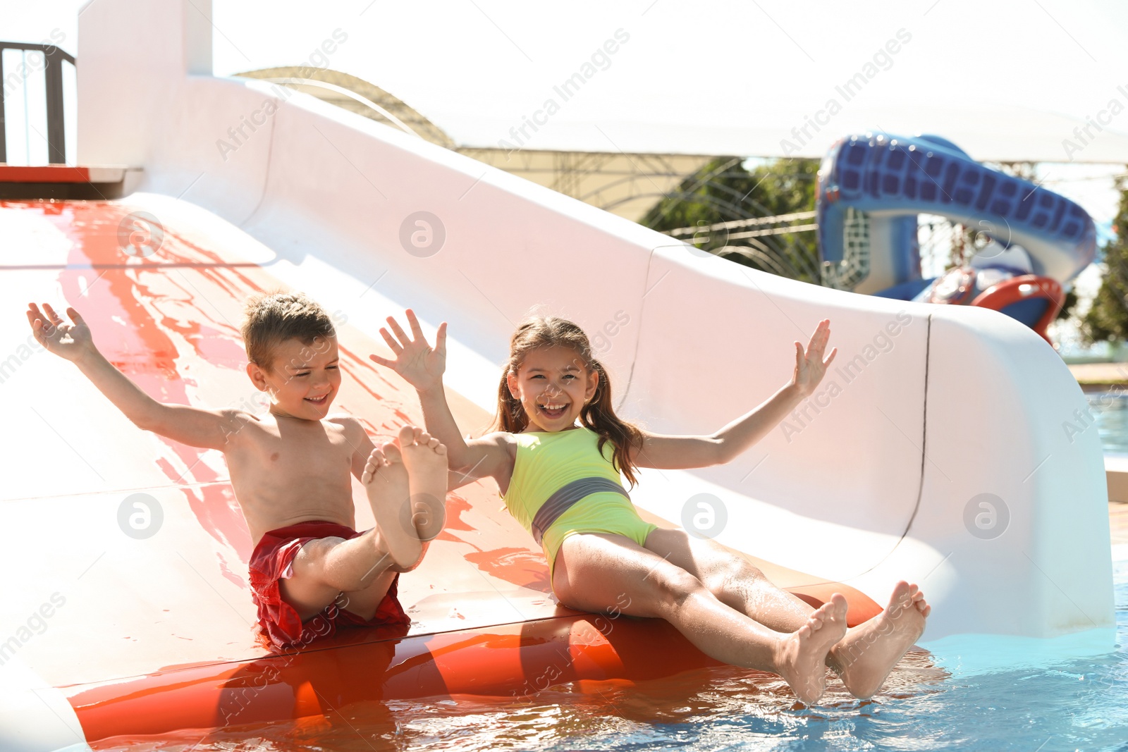 Photo of Happy children on slide at water park. Summer vacation