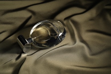 Photo of Luxury perfume in bottle on dark silk fabric
