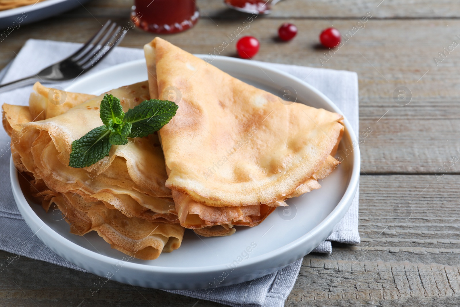 Photo of Delicious crepes served with mint on grey wooden table, closeup