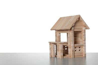 Photo of Wooden building on light grey table against white background, space for text. Children's toy