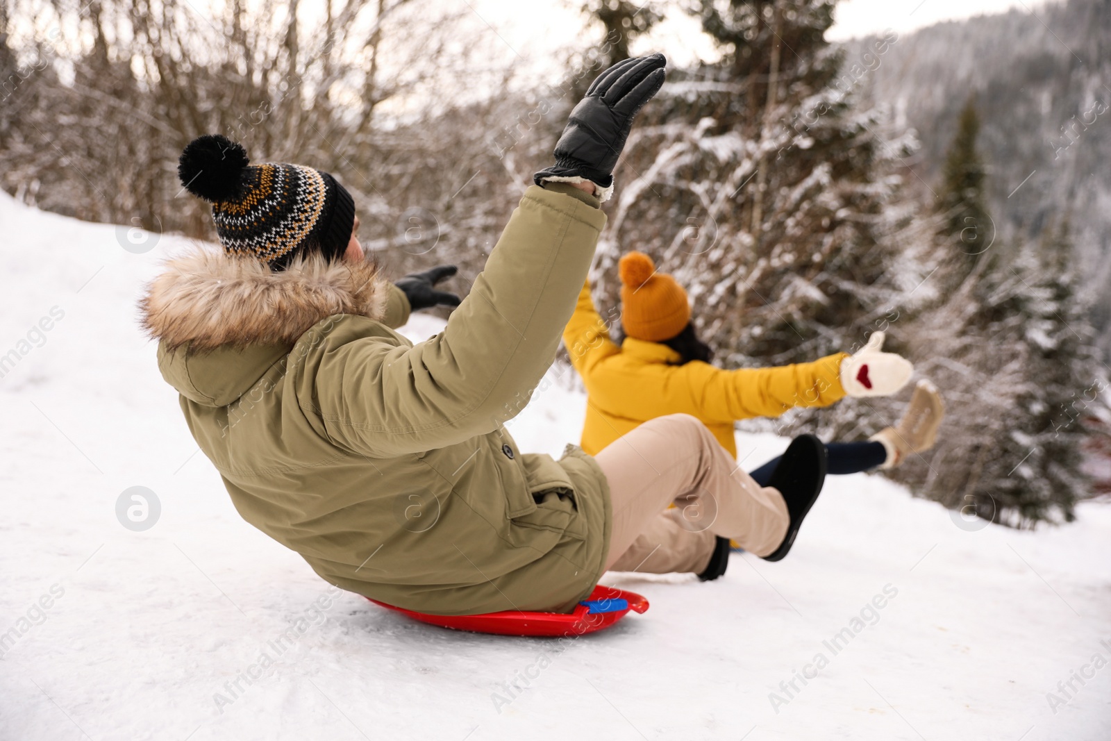 Photo of Couple sliding on snowy hill. Winter vacation