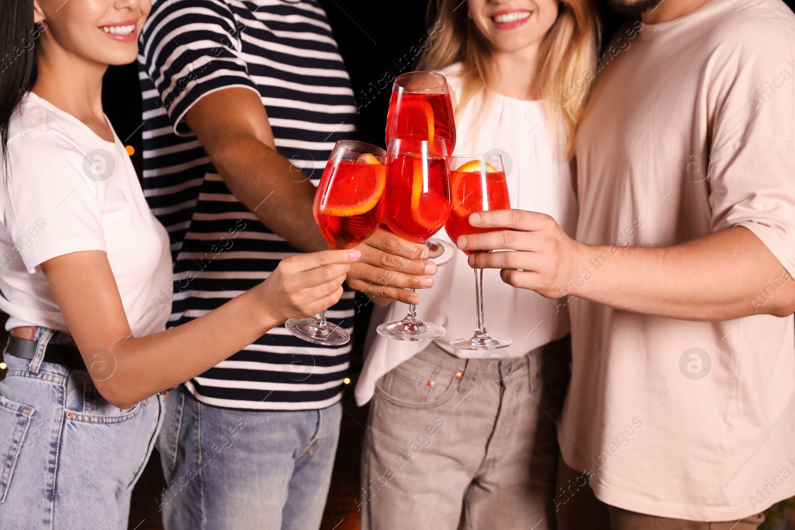 Photo of Friends with glasses of cocktails spending time together on cafe terrace at night, closeup