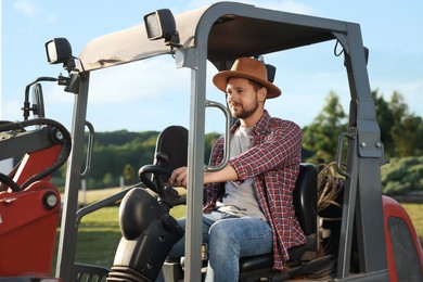 Farmer in hat driving loader outdoors. Agriculture equipment