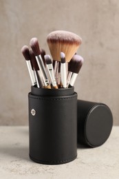 Photo of Set of professional makeup brushes on wooden table against light grey background