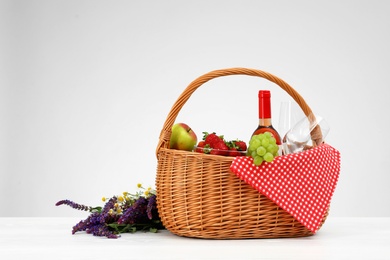 Photo of Picnic basket with wine, glasses and products on white background