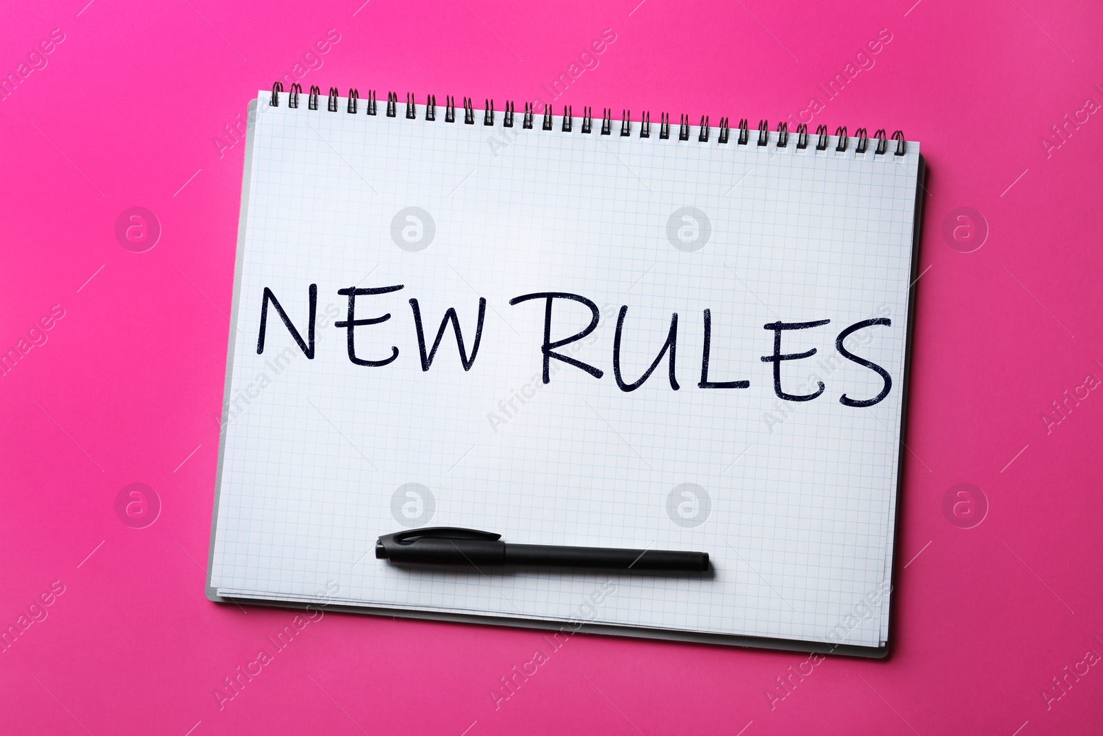 Image of Notebook with text NEW RULES and marker on color background, top view