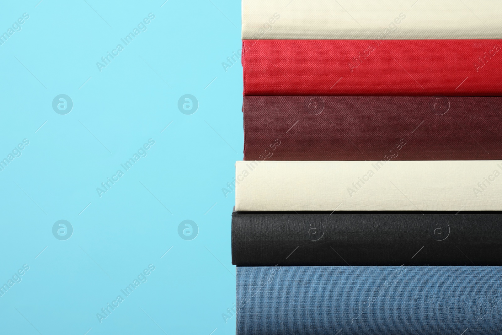 Photo of Stack of hardcover books on light blue background, space for text