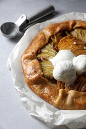 Photo of Delicious apple galette served with ice cream on light grey textured table, closeup