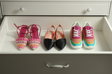 Photo of Different women's shoes in open drawer. Footwear storage