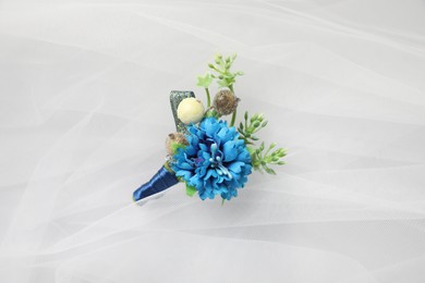 Photo of Wedding stuff. Stylish boutonniere on white veil, top view