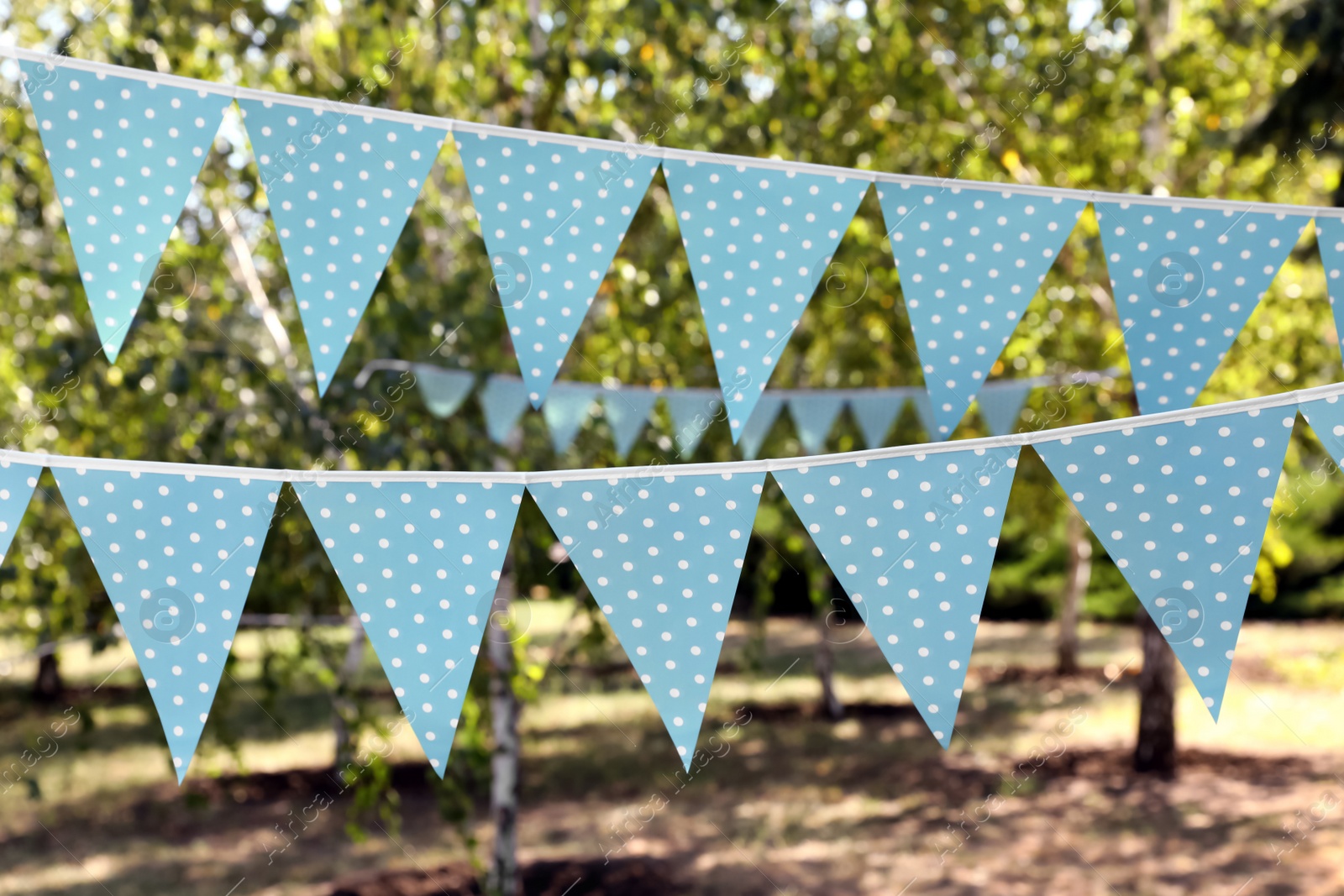 Photo of Light blue bunting flags in park. Party decor