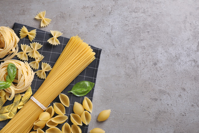 Flat lay composition with different types of pasta on grey background. Space for text