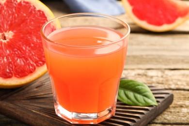 Photo of Glass of delicious grapefruit juice on wooden table, closeup