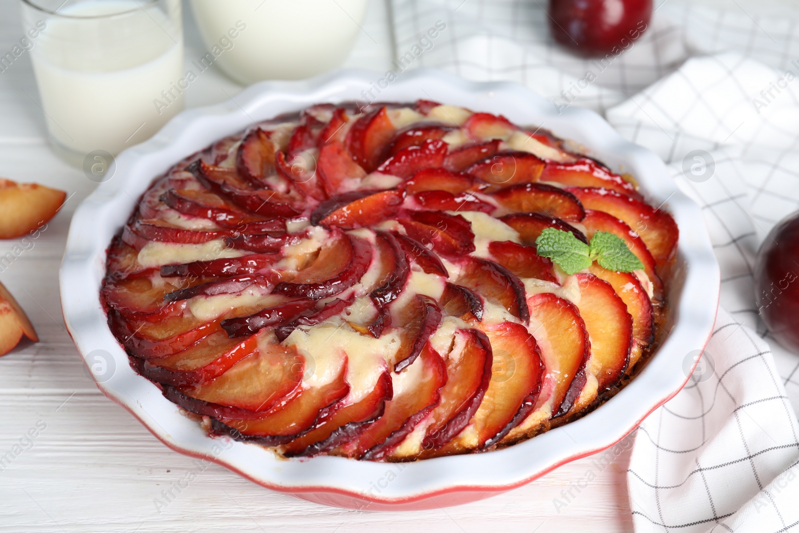 Photo of Delicious cake with plums on white wooden table, closeup