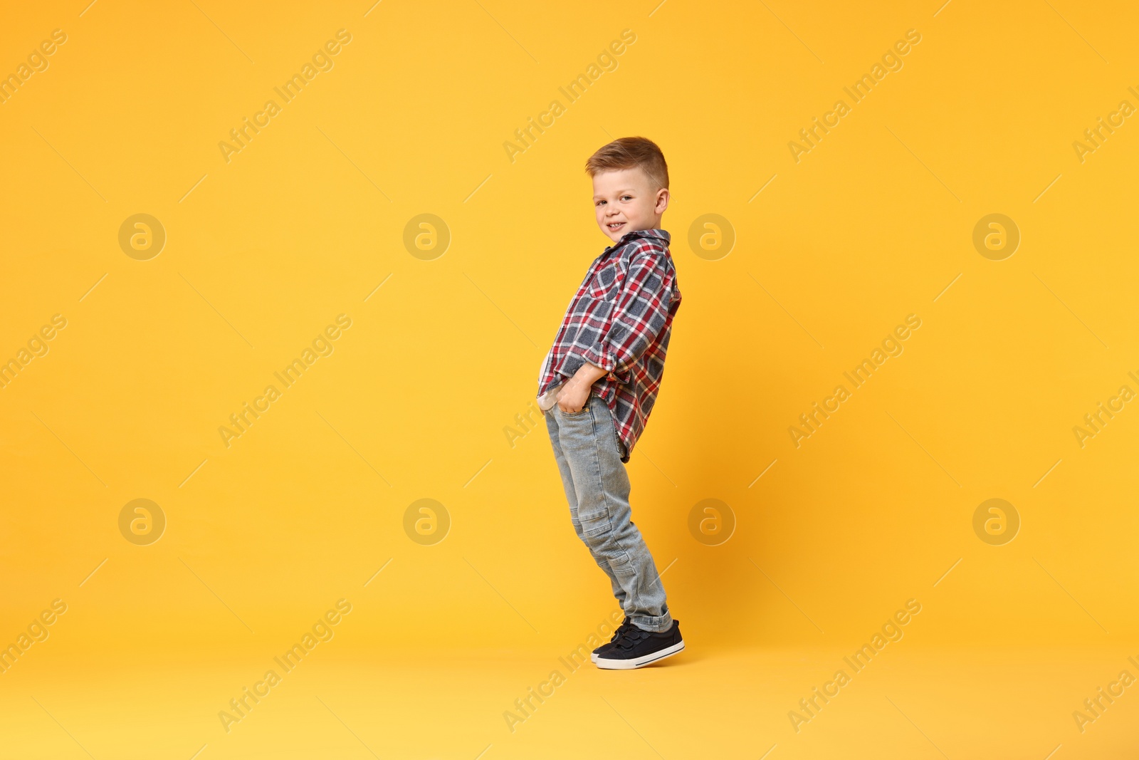 Photo of Happy little boy dancing on yellow background